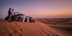 2 Hour Dune Buggy Convoy at Sunset - Lahbab Red Dunes Dubai Stunning sunset panorama of a dune buggy convoy parked on a red sand dune crest in Lahbab Desert Dubai, with dramatic orange and purple skies, capturing the beauty of a 2 hour group desert adventure