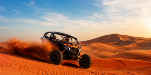Powerful morning dune buggy climbing red sand dunes at sunrise in Lahbab Desert Dubai with golden morning light and cool desert atmosphere
