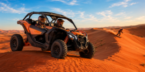 Morning dune buggy parked on red sand dune crest with person sandboarding down nearby slope in Lahbab Desert Dubai during golden sunrise hour