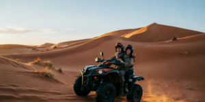 2-Seater Quad Bike for Couples at Lahbab Red Dunes – Dubai Desert Adventure Happy couple riding a 2-seater quad bike through the Lahbab Red Dunes in Dubai during golden sunset hour