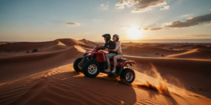 Couple riding a 2-seater quad bike together across the red sand dunes of the Lahbab Desert in Dubai during golden sunset hour